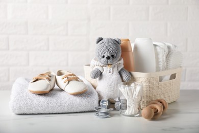Photo of Many different baby accessories and toy bear on table near brick wall