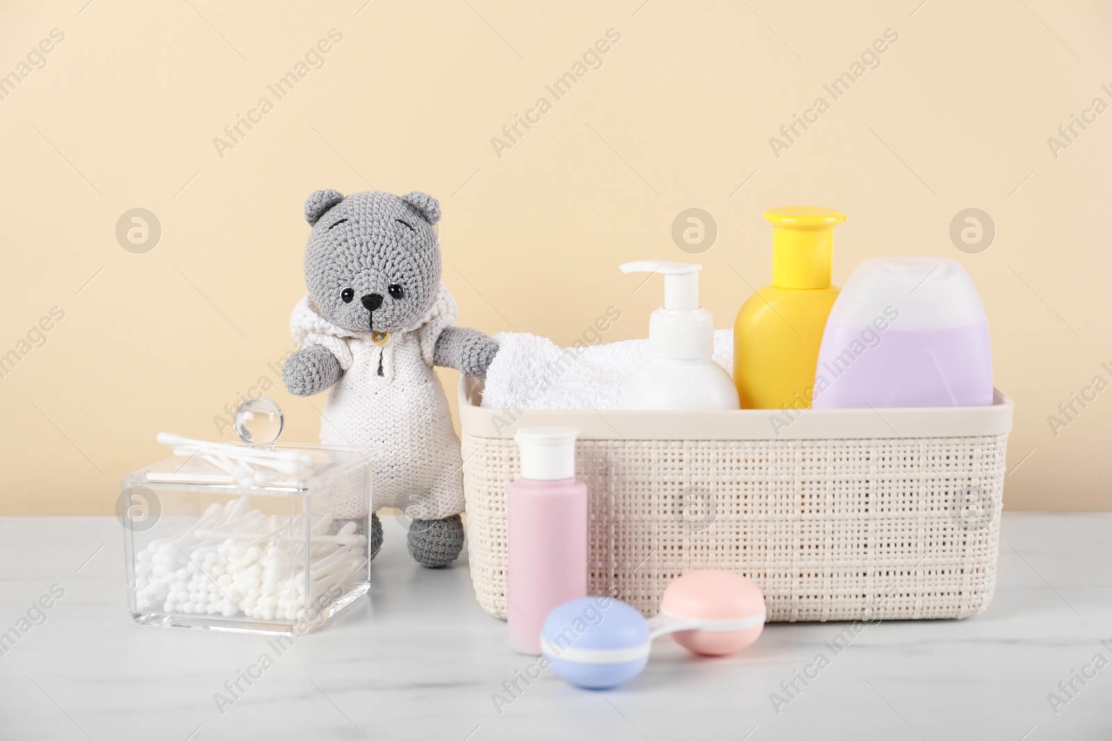 Photo of Different baby accessories and toy bear on table against beige background