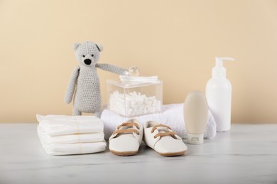 Photo of Different baby accessories and toy bear on table against beige background