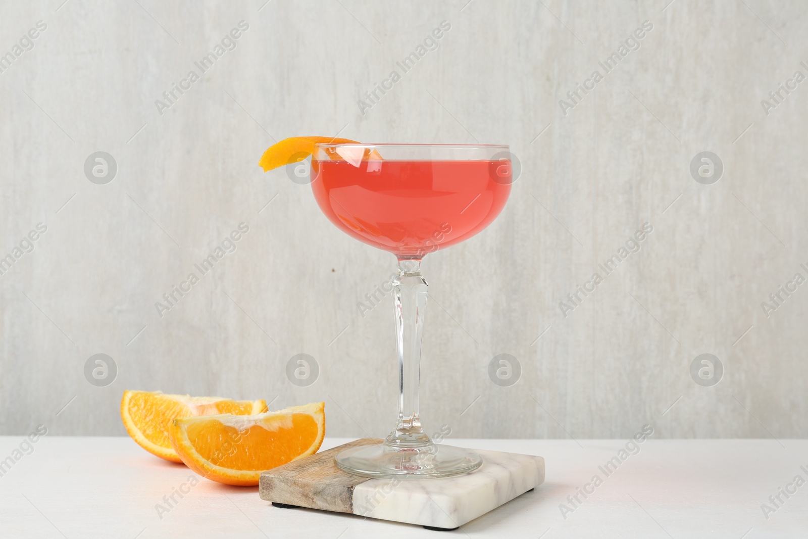 Martini cocktail with garnish and slices of orange on white table Photo of Martini cocktail with garnish and slices of orange on white table
