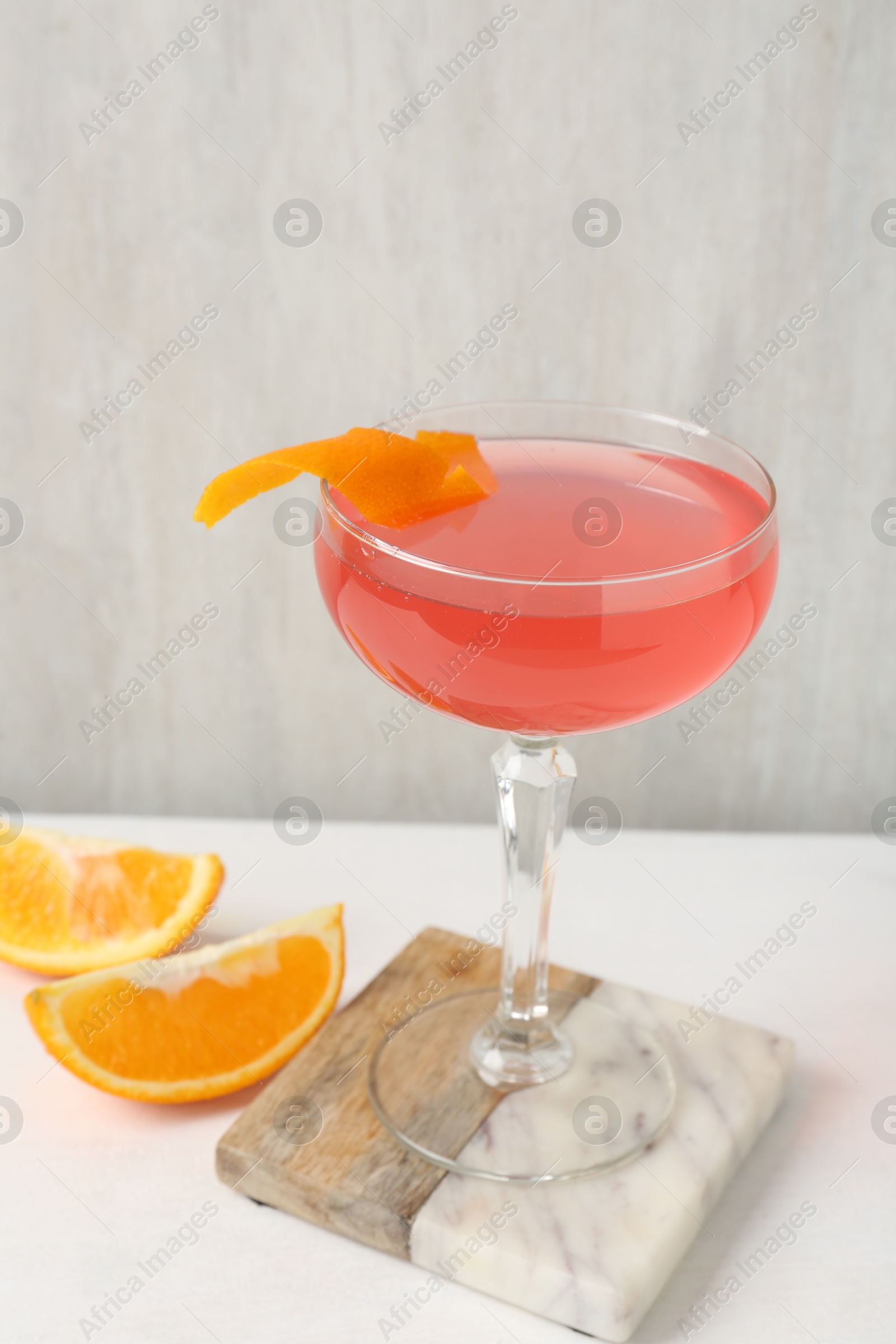 Martini cocktail with garnish and slices of orange on white table, closeup Photo of Martini cocktail with garnish and slices of orange on white table, closeup
