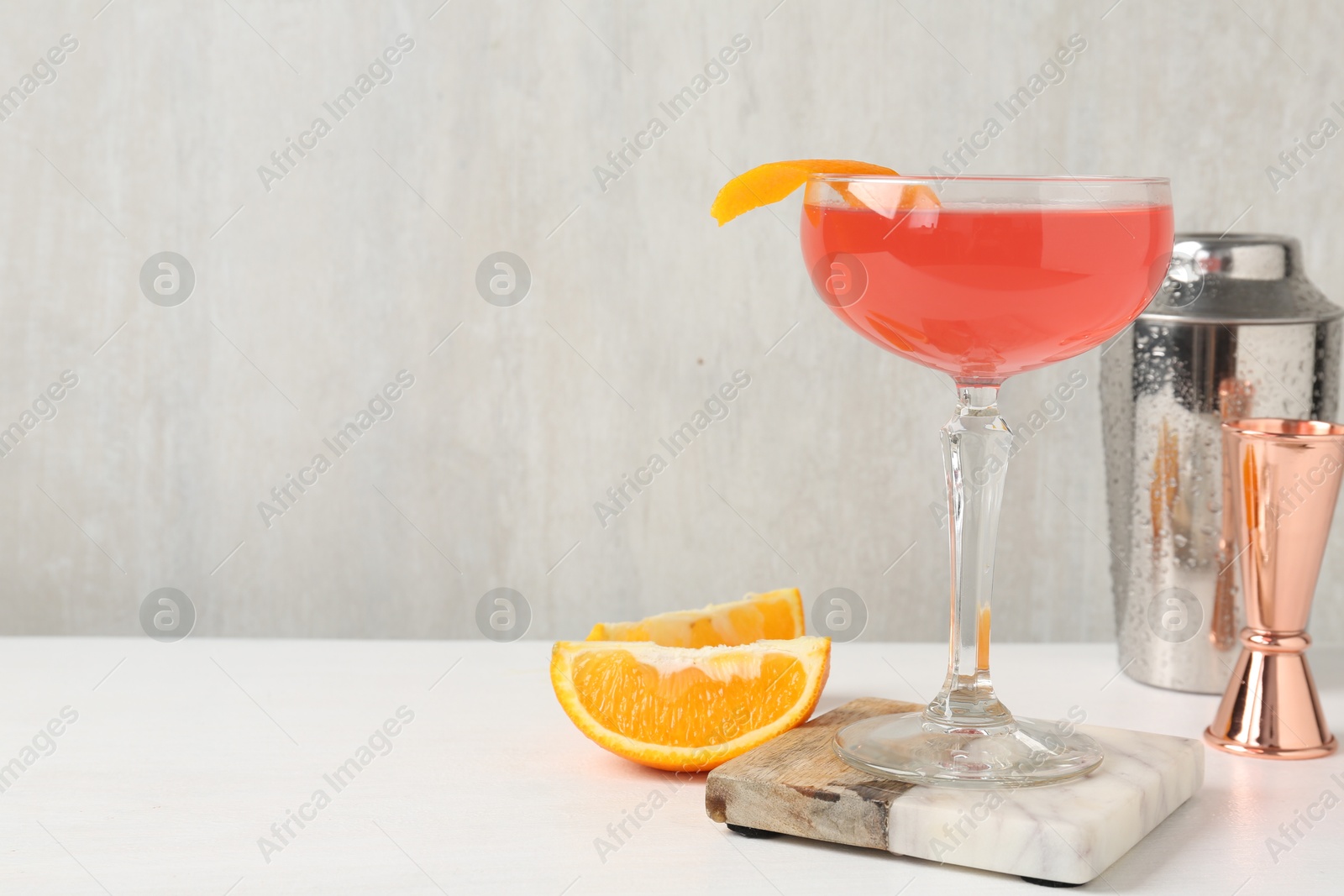 Martini cocktail with garnish, slices of orange and bartender equipment on white table, closeup. Space for text Photo of Martini cocktail with garnish, slices of orange and bartender equipment on white table, closeup. Space for text