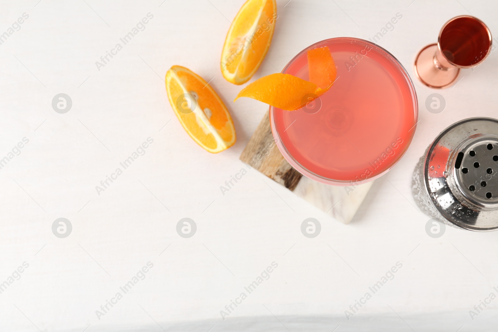 Martini cocktail with garnish, slices of orange and bartender equipment on white table, flat lay. Space for text Photo of Martini cocktail with garnish, slices of orange and bartender equipment on white table, flat lay. Space for text