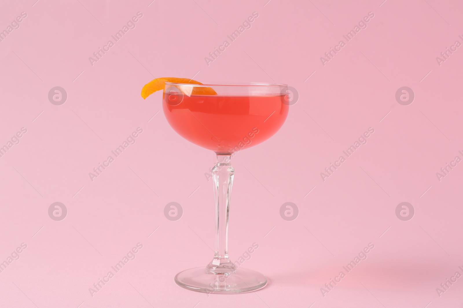 Martini cocktail with garnish on pink background Photo of Martini cocktail with garnish on pink background