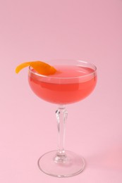 Photo of Martini cocktail with garnish on pink background, closeup