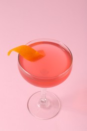 Photo of Martini cocktail with garnish on pink background, closeup