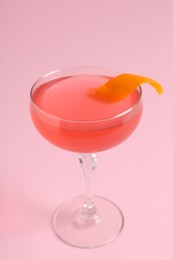 Photo of Martini cocktail with garnish on pink background, closeup