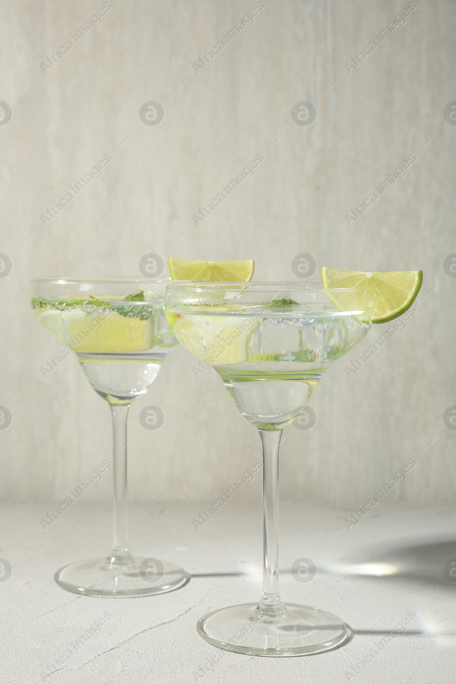 Martini cocktails with lime and mint on grey table Photo of Martini cocktails with lime and mint on grey table