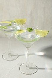 Photo of Martini cocktails with lime and mint on grey table, closeup