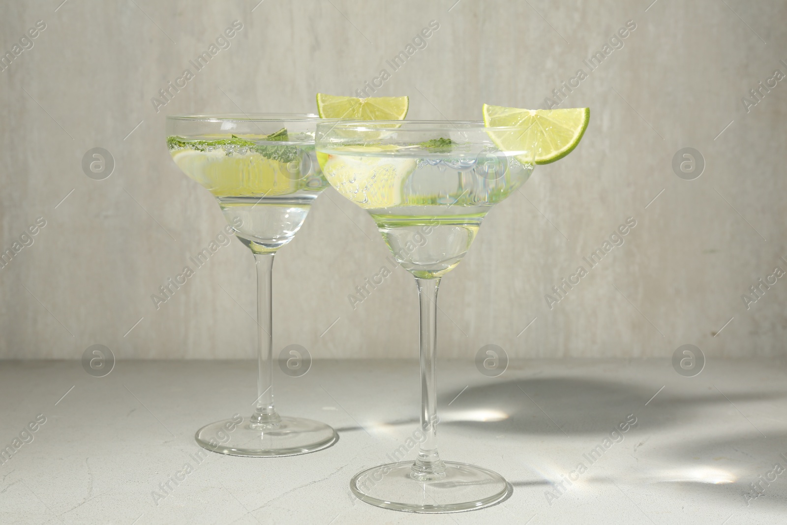 Martini cocktails with lime and mint on grey table Photo of Martini cocktails with lime and mint on grey table