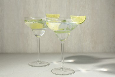 Photo of Martini cocktails with lime and mint on grey table