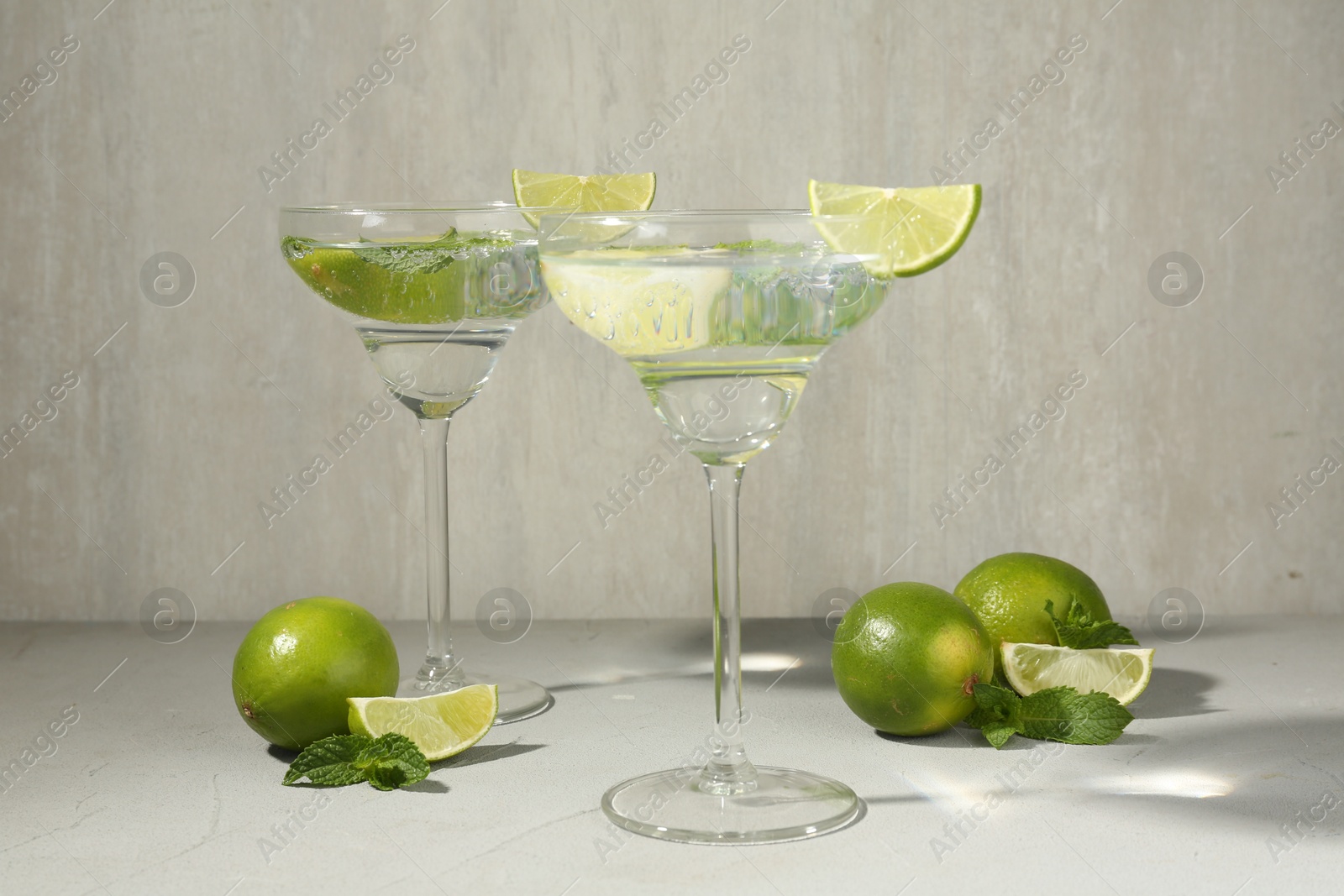 Martini cocktails with lime and mint on grey table Photo of Martini cocktails with lime and mint on grey table