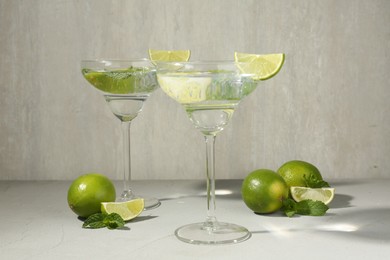 Photo of Martini cocktails with lime and mint on grey table
