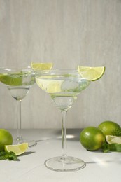 Photo of Martini cocktails with lime and mint on grey table, closeup