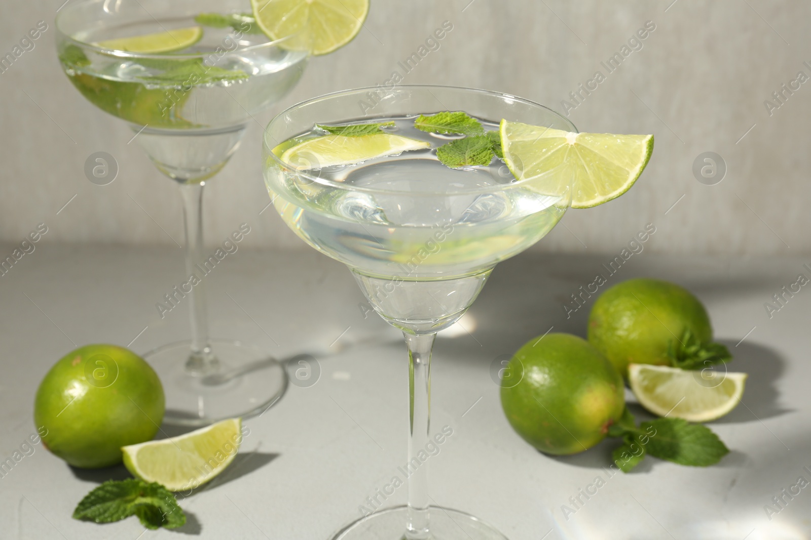 Martini cocktails with lime and mint on grey table, closeup Photo of Martini cocktails with lime and mint on grey table, closeup