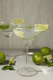 Photo of Martini cocktails with lime and mint on grey table, closeup