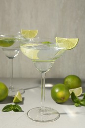 Photo of Martini cocktails with lime and mint on grey table, closeup