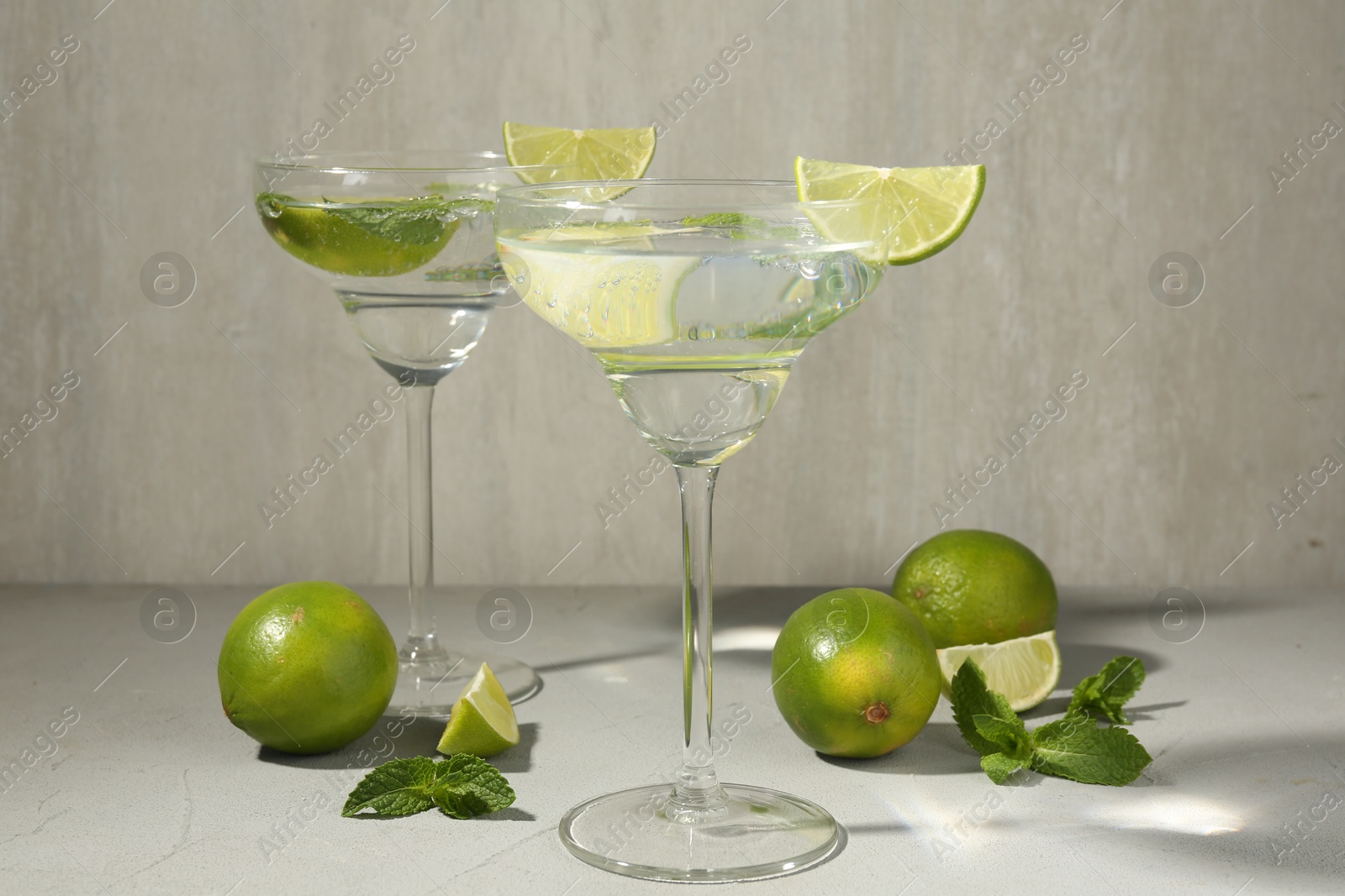 Martini cocktails with lime and mint on grey table, closeup Photo of Martini cocktails with lime and mint on grey table, closeup