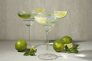 Photo of Martini cocktails with lime and mint on grey table, closeup