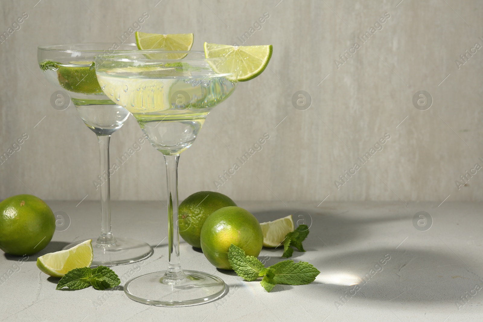 Martini cocktails with lime and mint on grey table, space for text Photo of Martini cocktails with lime and mint on grey table, space for text