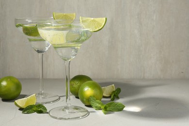 Photo of Martini cocktails with lime and mint on grey table, space for text