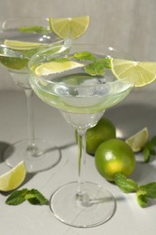 Photo of Martini cocktails with lime and mint on grey table, closeup