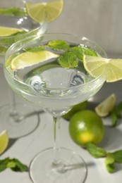Photo of Martini cocktails with lime and mint on grey table, closeup