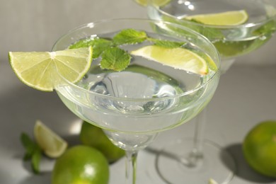 Photo of Martini cocktails with lime and mint on grey table, closeup
