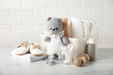 Photo of Many different baby accessories and toy bear on table near brick wall