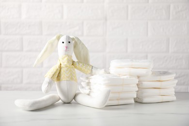 Photo of Baby diapers and toy bunny on white table near brick wall