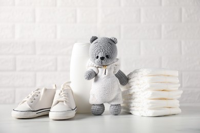 Photo of Many different baby accessories and toy bear on table near brick wall