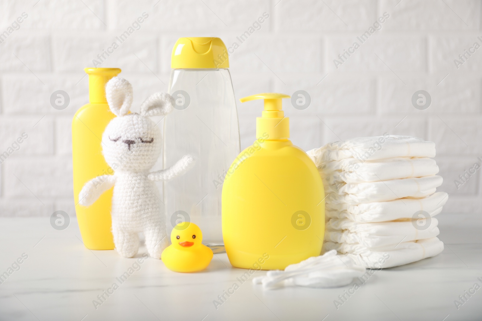 Photo of Many different baby accessories and toy bunny on table near brick wall