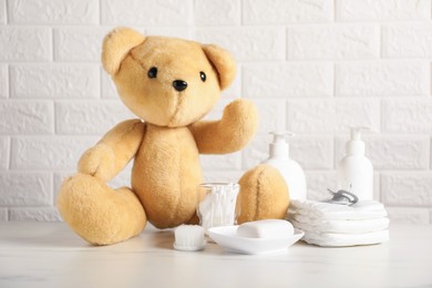 Photo of Many different baby accessories and toy bear on table near brick wall