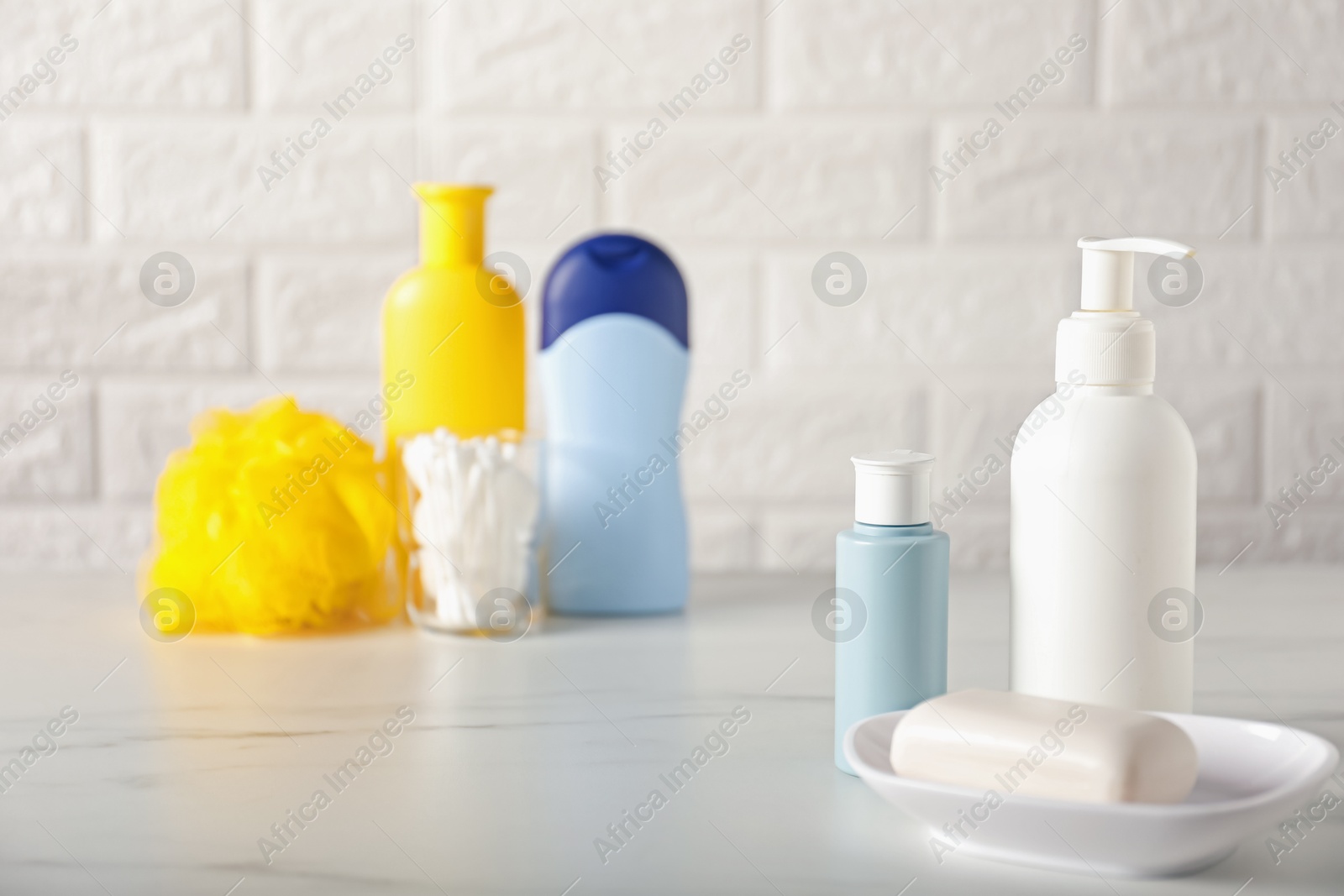 Photo of Many different baby bathroom necessities on table near brick wall, selective focus