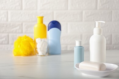 Photo of Many different baby bathroom necessities on table near brick wall, selective focus