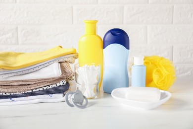 Photo of Different baby clothes and accessories on table near brick wall