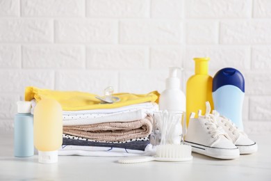 Photo of Different baby clothes and accessories on table near brick wall
