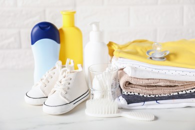 Photo of Different baby clothes and accessories on table near brick wall