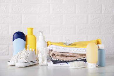 Photo of Different baby clothes and accessories on table near brick wall