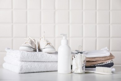 Photo of Different baby clothes and accessories on table near tiled wall