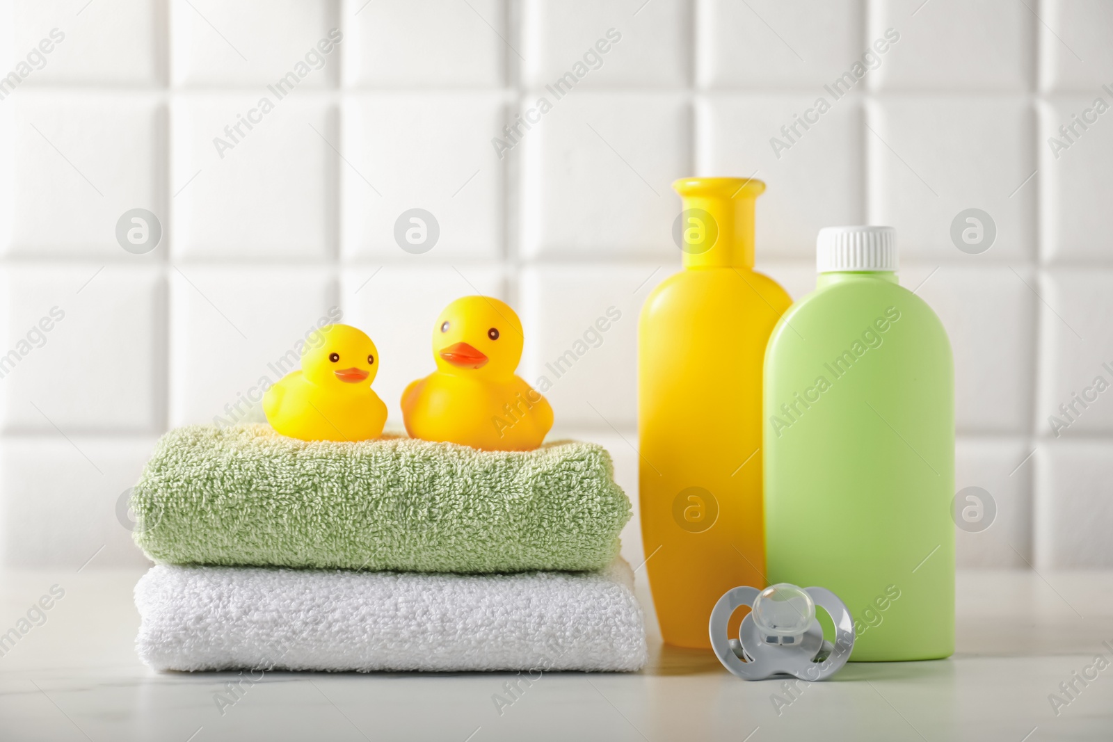 Photo of Many different baby bathroom necessities on table near tiled wall