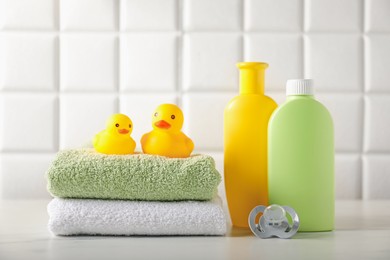 Photo of Many different baby bathroom necessities on table near tiled wall