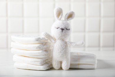 Photo of Baby diapers and toy bunny on white table near tiled wall