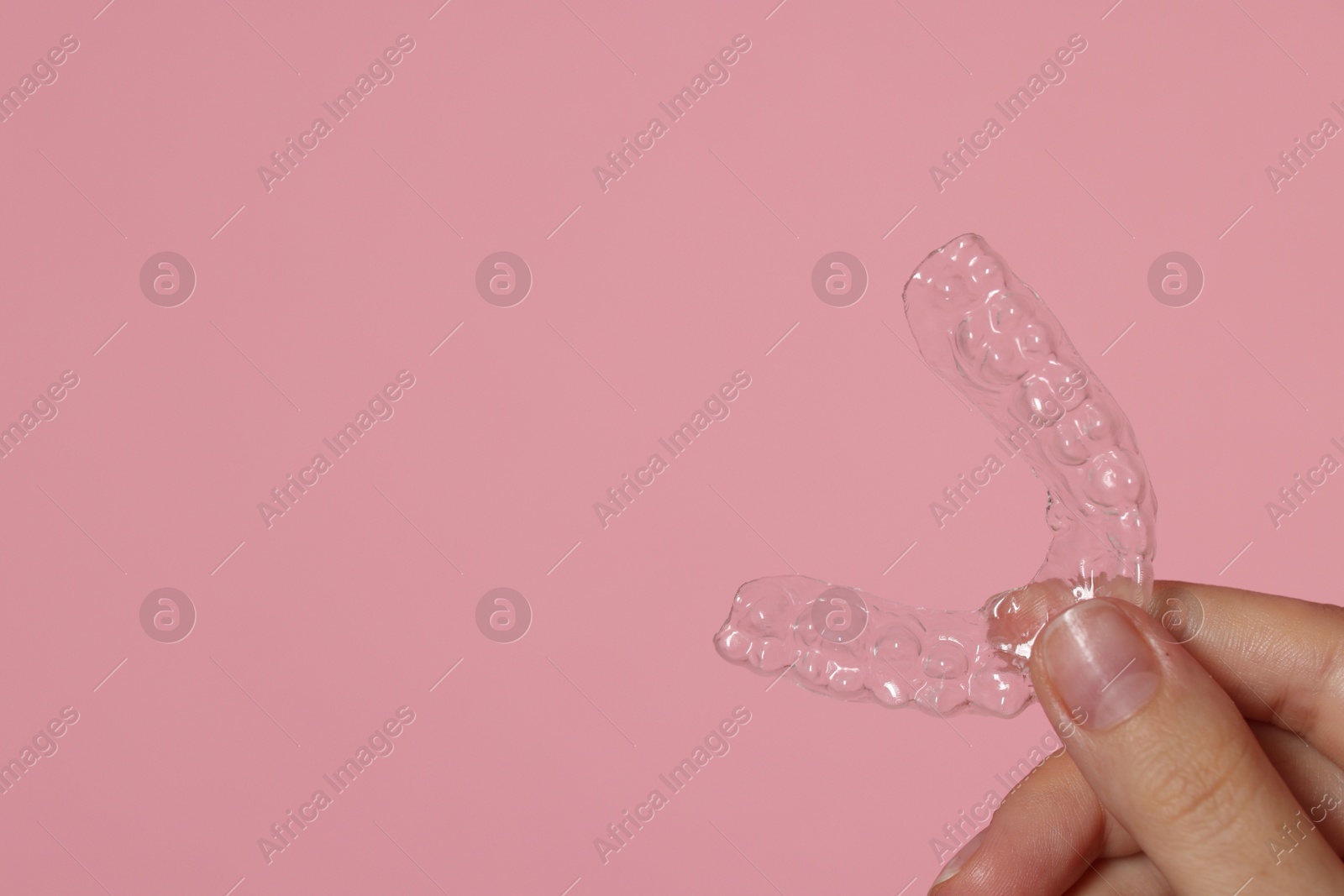 Woman with dental aligner on pink background, closeup. Space for text Photo of Woman with dental aligner on pink background, closeup. Space for text