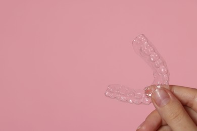 Photo of Woman with dental aligner on pink background, closeup. Space for text