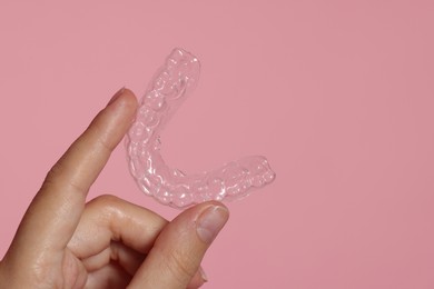 Photo of Woman with dental aligner on pink background, closeup
