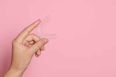 Photo of Woman with dental aligner on pink background, closeup. Space for text