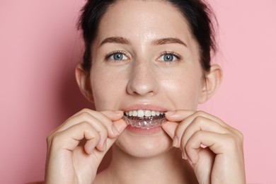 Photo of Beautiful woman wearing dental aligner on pink background, closeup