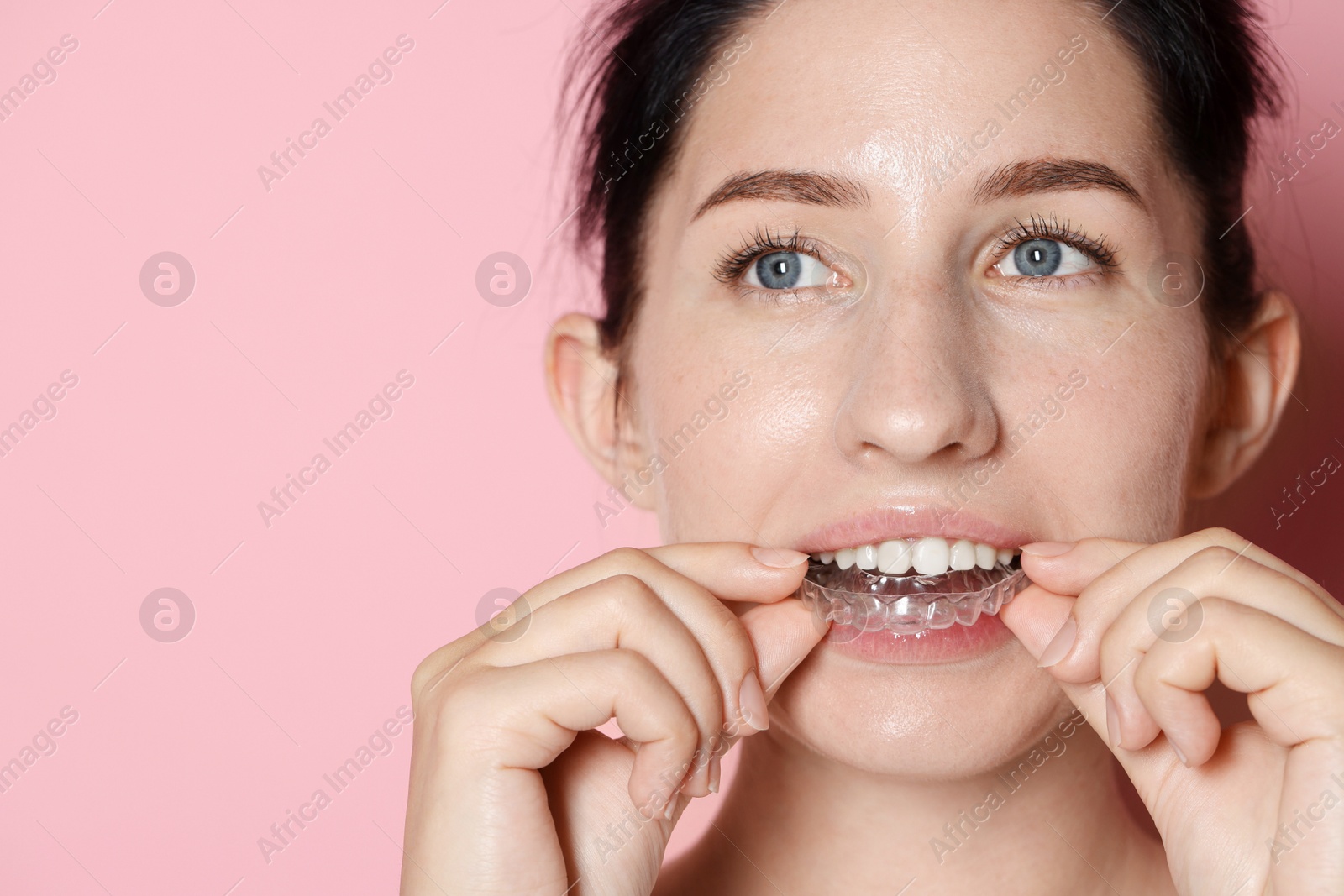 Woman wearing dental aligner on pink background, closeup. Space for text Photo of Woman wearing dental aligner on pink background, closeup. Space for text