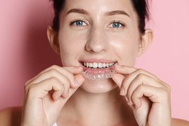 Photo of Beautiful woman wearing dental aligner on pink background, closeup